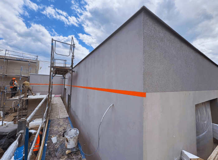 Průběh kompletní realizace a zateplení fasády o ploše 1000 $m^2$ v Blansku od firmy Misterstav. Fotografie detailně zachycují pokládku polystyrenu, armování perlinkou kolem oken a aplikaci finální moderní šedé omítky.