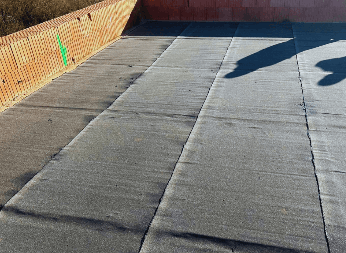 Dronové záběry a detaily hotových plochých střech z PVC fólie a moderních šedých fasád na projektu Rezidence Lipové sady v Rousínově od firmy Mister stav s.r.o.. Fotografie zachycují precizní zpracování hydroizolace a zateplení celého komplexu novostaveb.