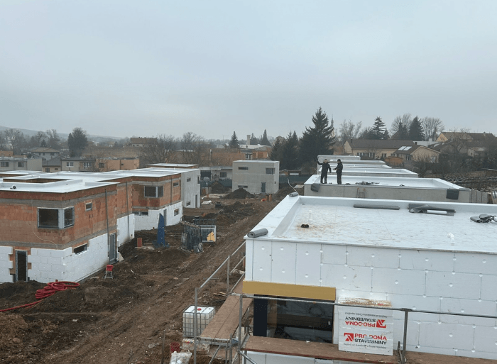Dronové záběry a detaily hotových plochých střech z PVC fólie a moderních šedých fasád na projektu Rezidence Lipové sady v Rousínově od firmy Mister stav s.r.o.. Fotografie zachycují precizní zpracování hydroizolace a zateplení celého komplexu novostaveb.