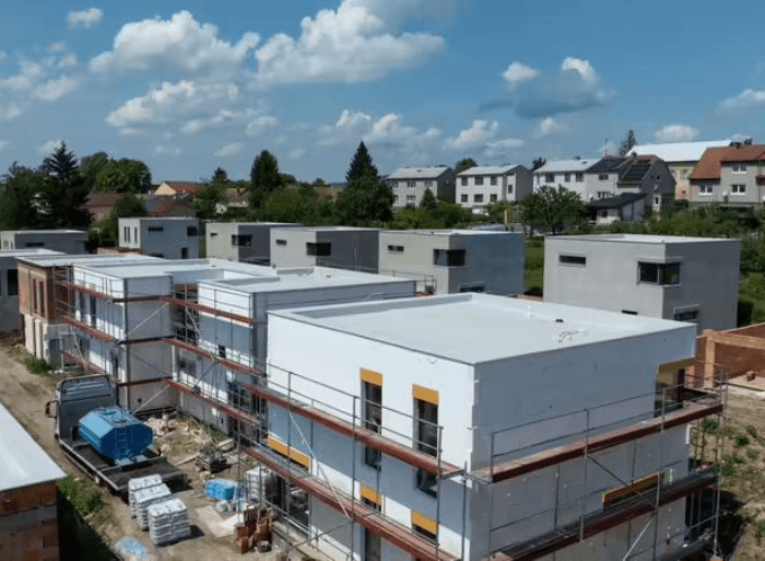 Dronové záběry a detaily hotových plochých střech z PVC fólie a moderních šedých fasád na projektu Rezidence Lipové sady v Rousínově od firmy Mister stav s.r.o.. Fotografie zachycují precizní zpracování hydroizolace a zateplení celého komplexu novostaveb.
