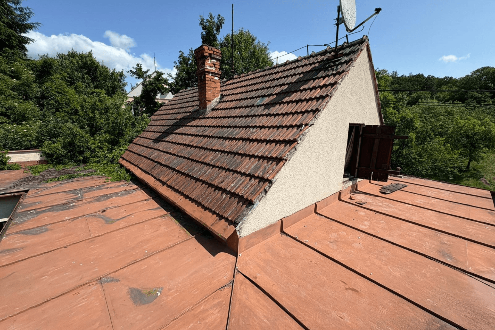 Komplexní rekonstrukce rodinného domu v Židlochovicích od firmy Misterstav. Fotografie zachycují výměnu sedlové střechy za novou skládanou krytinu, pokládku izolace a svařování PVC fólie na ploché terase a realizaci nové zateplené bílé fasády.