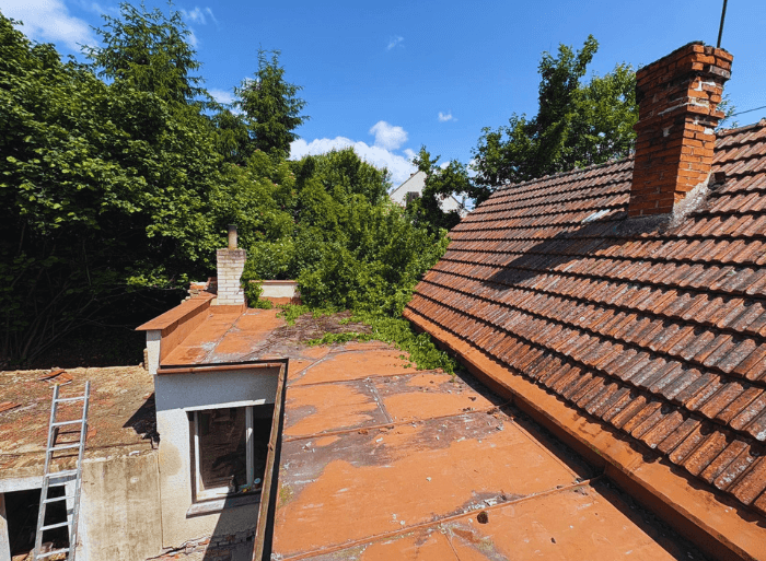 Komplexní rekonstrukce rodinného domu v Židlochovicích od firmy Misterstav. Fotografie zachycují výměnu sedlové střechy za novou skládanou krytinu, pokládku izolace a svařování PVC fólie na ploché terase a realizaci nové zateplené bílé fasády.